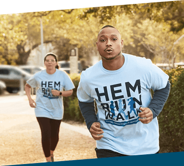 A man and a woman wearing the Hemo Walk t-shirt while running.